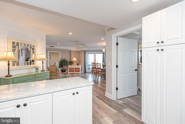 kitchen with white cabinetry, light stone counters, ceiling fan, and light wood-type flooring