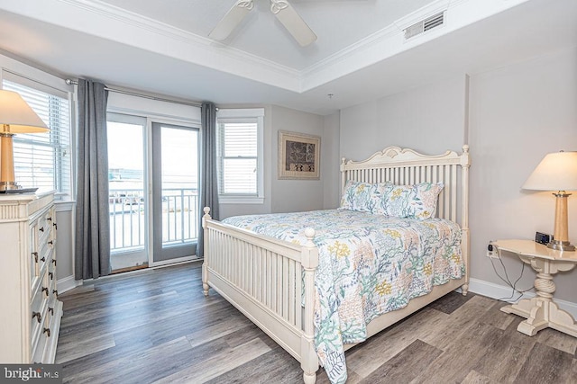 bedroom featuring a raised ceiling, crown molding, hardwood / wood-style floors, and access to outside