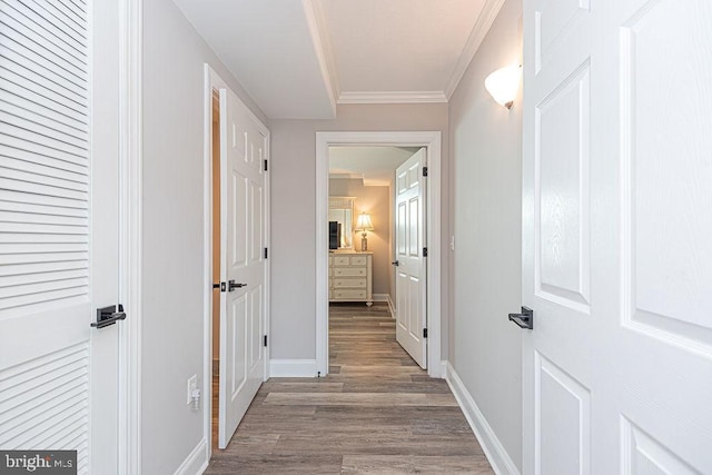 corridor featuring wood-type flooring and ornamental molding