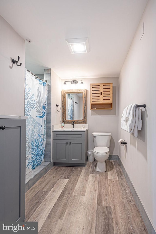 bathroom with hardwood / wood-style flooring, vanity, curtained shower, and toilet