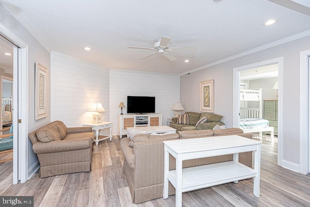 living room featuring crown molding, ceiling fan, and light hardwood / wood-style floors