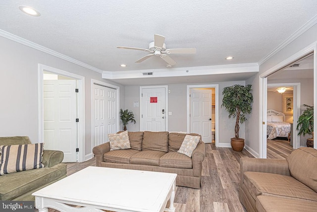 living room with a textured ceiling, ornamental molding, light hardwood / wood-style floors, and ceiling fan