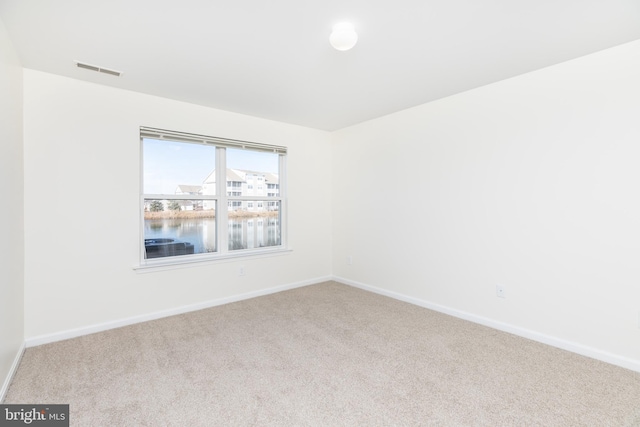 unfurnished room with a water view and carpet