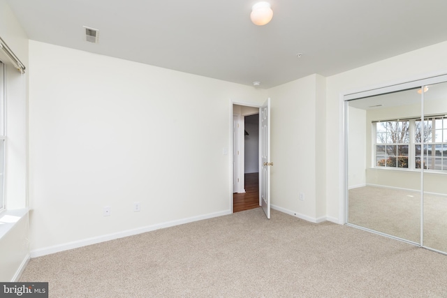 unfurnished bedroom featuring light carpet and a closet