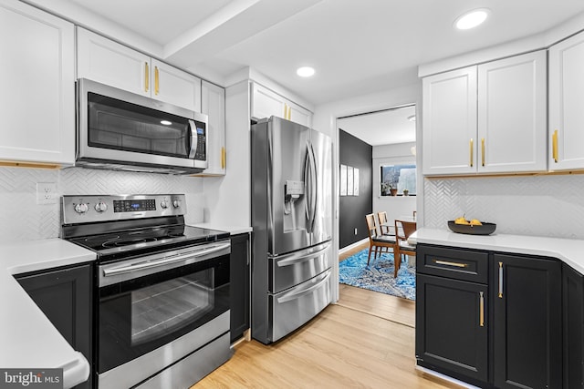 kitchen featuring white cabinetry, appliances with stainless steel finishes, backsplash, and light wood-type flooring