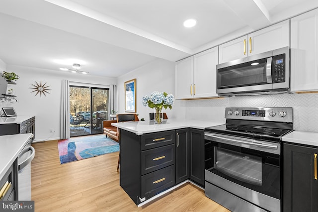 kitchen featuring white cabinetry, appliances with stainless steel finishes, kitchen peninsula, light hardwood / wood-style floors, and backsplash