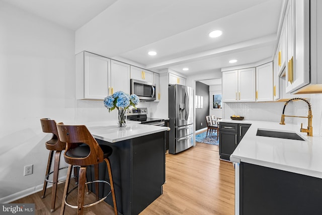 kitchen featuring appliances with stainless steel finishes, sink, light hardwood / wood-style flooring, and white cabinets