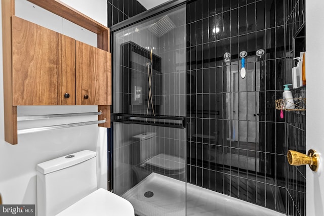 bathroom featuring a shower with door and toilet