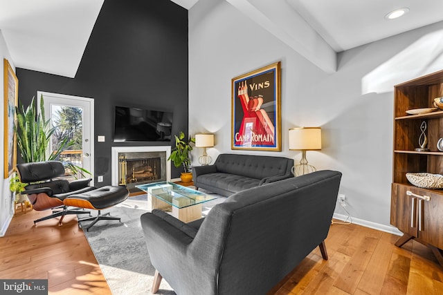 living room featuring beamed ceiling and light hardwood / wood-style floors