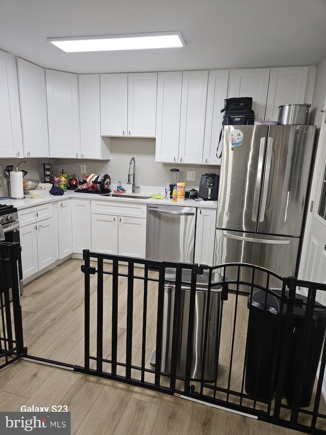 kitchen featuring white cabinetry, appliances with stainless steel finishes, light hardwood / wood-style floors, and sink