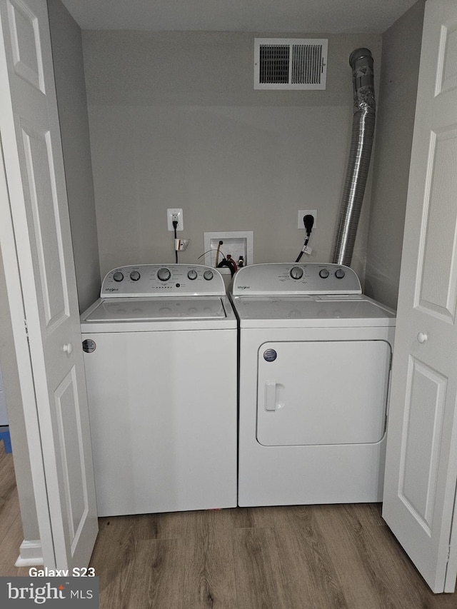 clothes washing area with washing machine and dryer and hardwood / wood-style floors