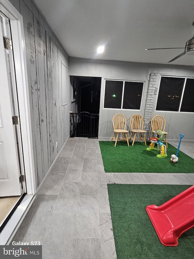 playroom featuring wooden walls and ceiling fan