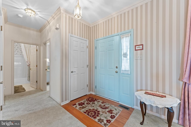 entryway with ornamental molding and light hardwood / wood-style floors