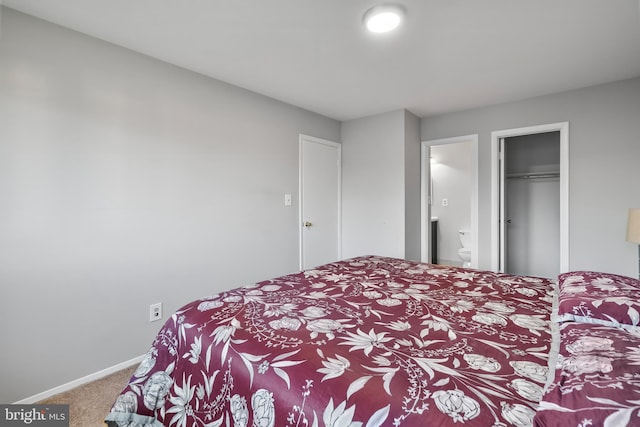 carpeted bedroom featuring a closet, ensuite bathroom, and baseboards