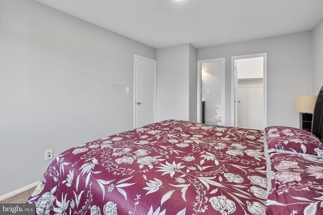 carpeted bedroom featuring a closet, ensuite bathroom, and baseboards