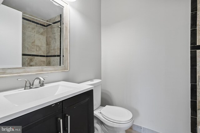 full bathroom with a tile shower, toilet, and vanity