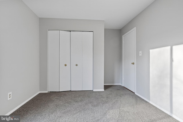 unfurnished bedroom featuring carpet, baseboards, and a closet