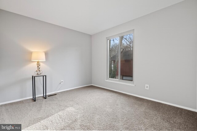 carpeted spare room featuring visible vents and baseboards