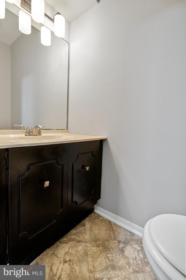 bathroom featuring vanity, toilet, and baseboards