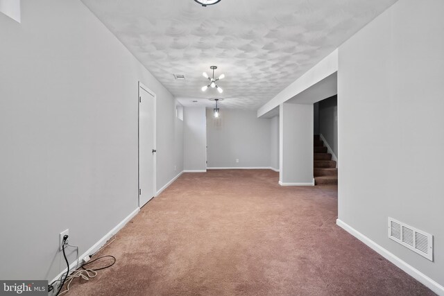 finished below grade area featuring stairway, carpet flooring, baseboards, and visible vents