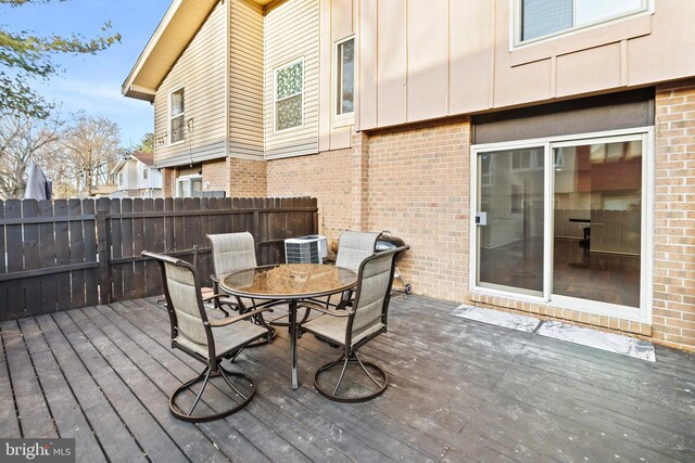 deck featuring central AC unit, outdoor dining area, and fence