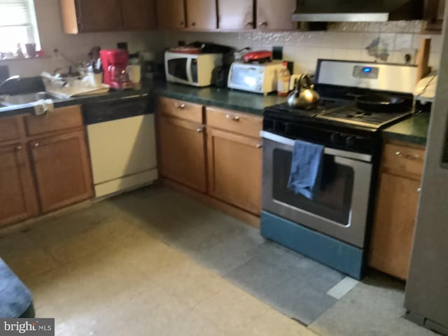 kitchen featuring dishwashing machine, sink, and stainless steel gas range oven