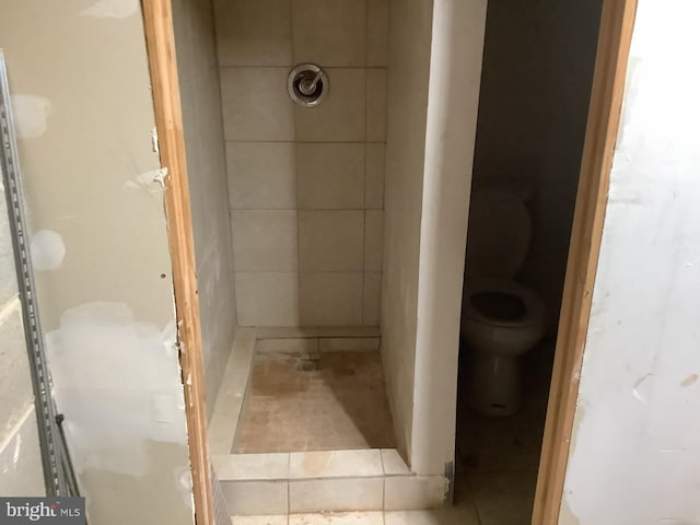 bathroom featuring tiled shower and toilet