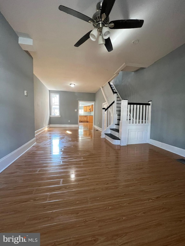 unfurnished living room featuring dark wood-type flooring and ceiling fan