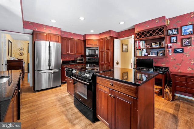 kitchen with light wood-type flooring, a kitchen island, dark stone countertops, and black appliances