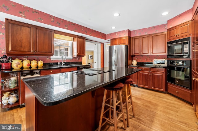 kitchen featuring light wood-type flooring, sink, black appliances, and a kitchen island