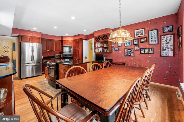 dining area with light wood-type flooring and a notable chandelier