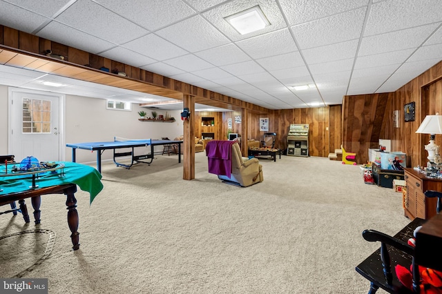 rec room featuring carpet, a paneled ceiling, and wood walls