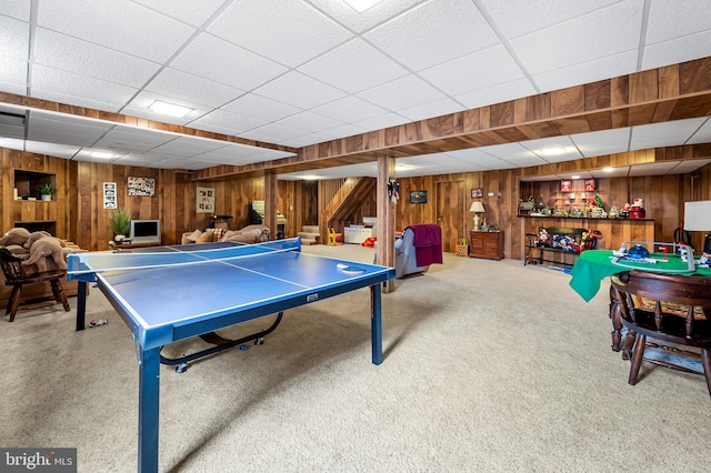 game room with a paneled ceiling, wooden walls, and carpet flooring