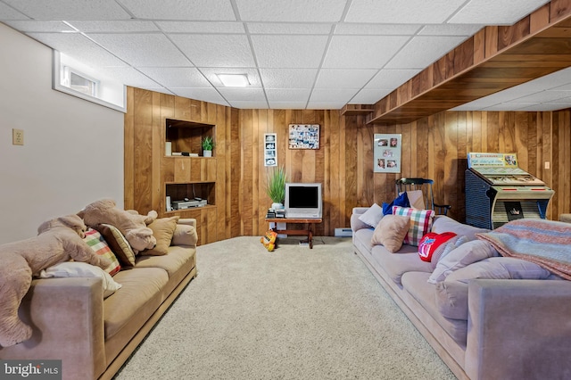 living room featuring carpet, wooden walls, and a paneled ceiling