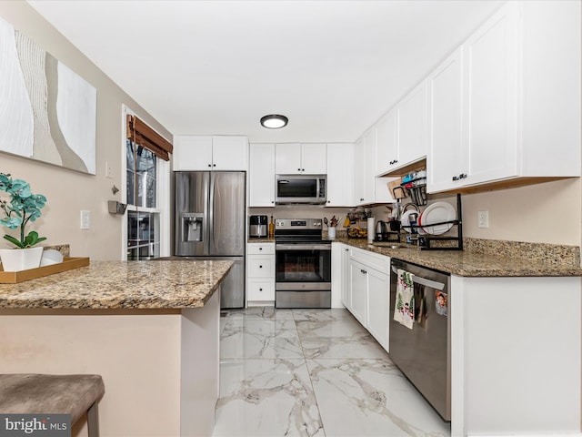 kitchen with appliances with stainless steel finishes, stone countertops, and white cabinets