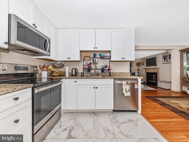 kitchen featuring white cabinetry, appliances with stainless steel finishes, sink, and dark stone counters