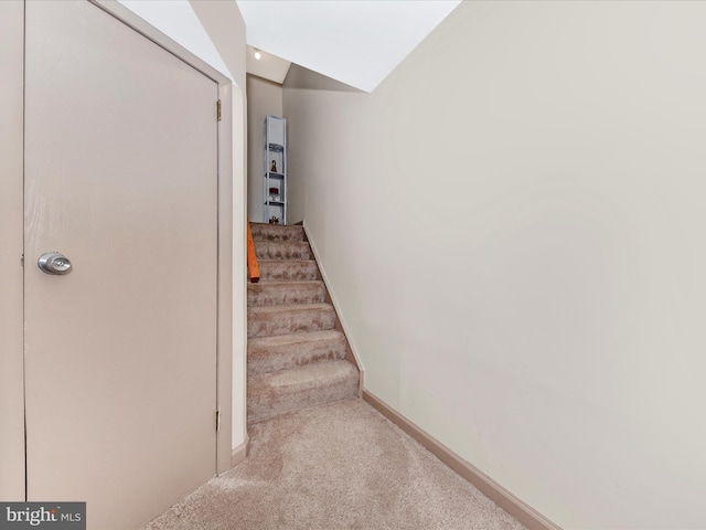 stairs with vaulted ceiling and carpet