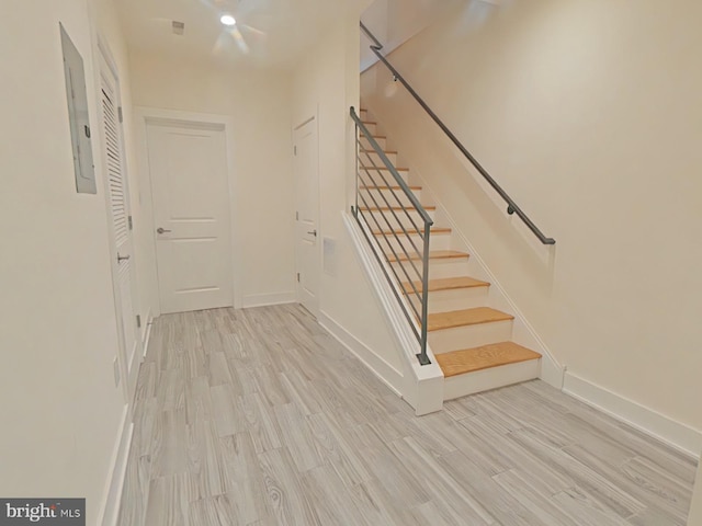 stairs featuring wood-type flooring and electric panel