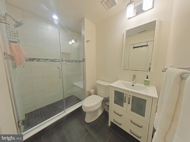 bathroom featuring tile patterned flooring, vanity, a shower with shower door, and toilet