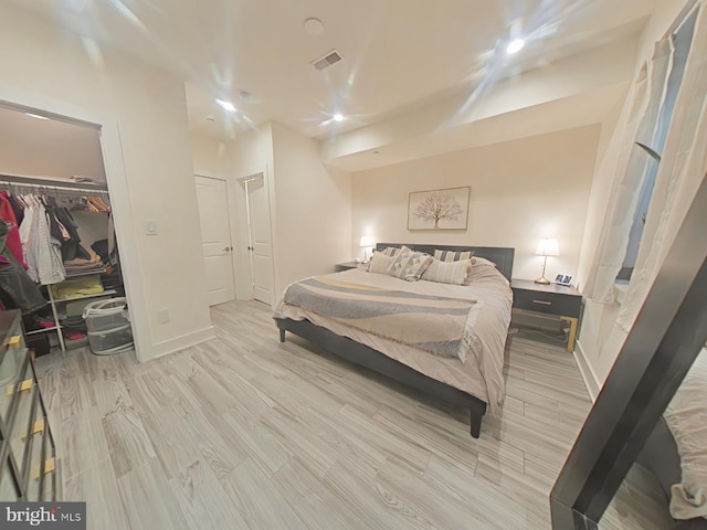 bedroom featuring a closet, a spacious closet, and light hardwood / wood-style flooring