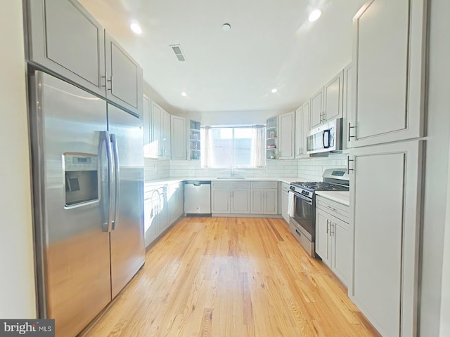 kitchen featuring stainless steel appliances, tasteful backsplash, gray cabinets, and sink