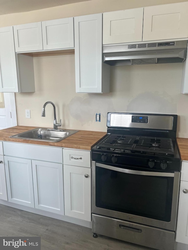 kitchen with sink, butcher block countertops, white cabinetry, stainless steel range with gas cooktop, and dark hardwood / wood-style flooring