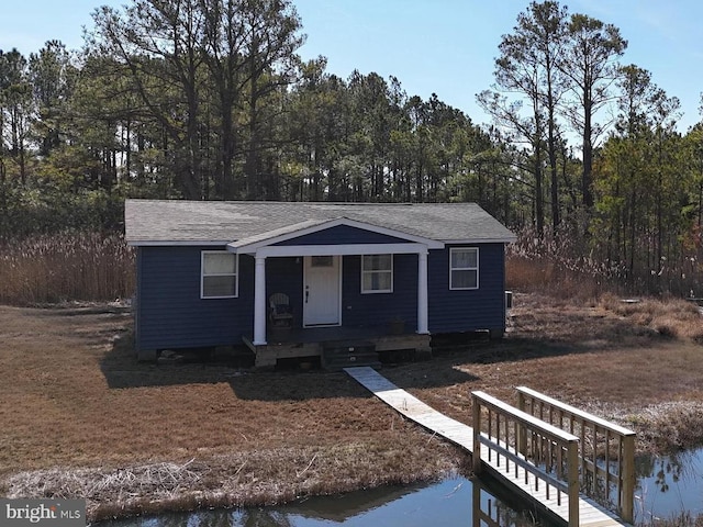 view of front of home with a water view, a porch, and roof with shingles