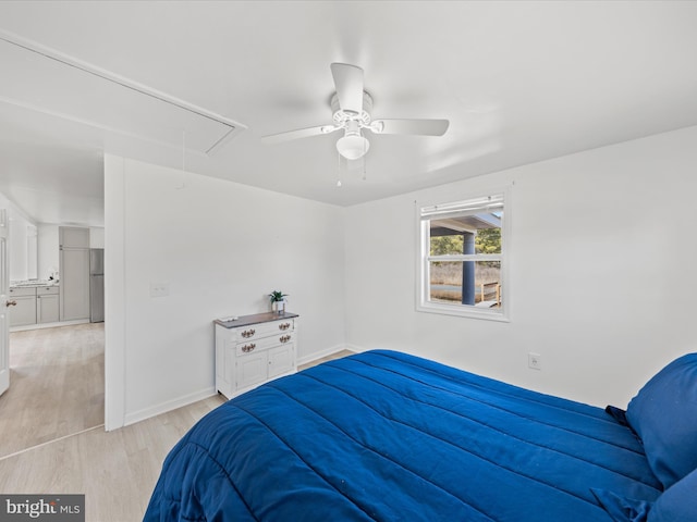 bedroom featuring attic access, baseboards, a ceiling fan, light wood-style flooring, and freestanding refrigerator