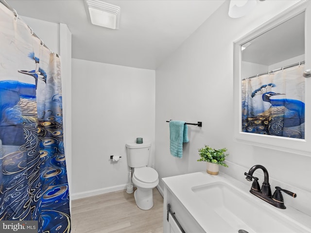 bathroom with baseboards, vanity, toilet, and wood finished floors