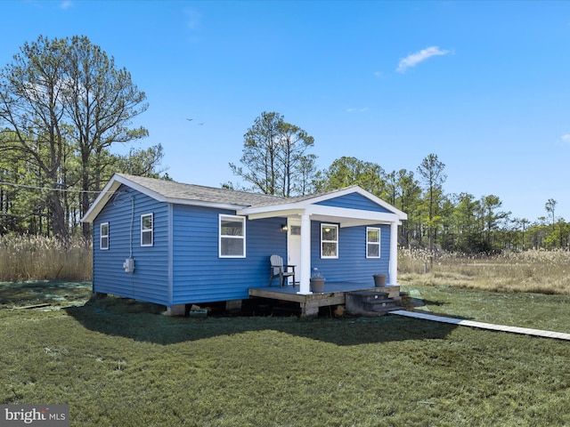 view of front of home with covered porch, a shingled roof, and a front lawn