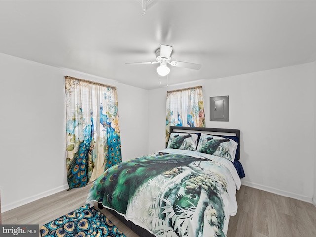 bedroom featuring electric panel, baseboards, and wood finished floors