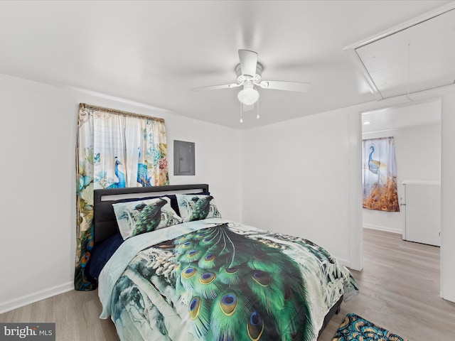 bedroom with ceiling fan, wood finished floors, baseboards, electric panel, and attic access