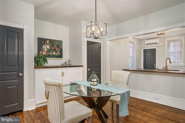 dining area featuring an inviting chandelier, sink, dark wood-type flooring, and a wall mounted AC