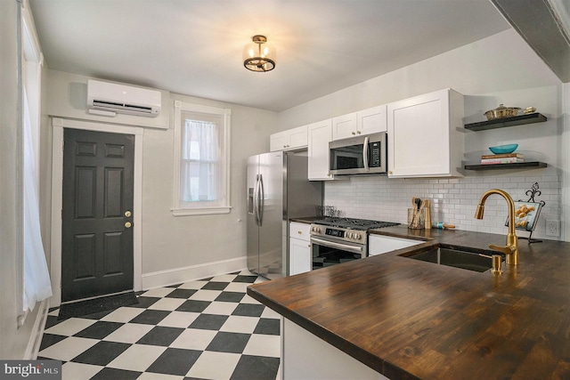 kitchen featuring sink, appliances with stainless steel finishes, a wall mounted AC, white cabinets, and kitchen peninsula